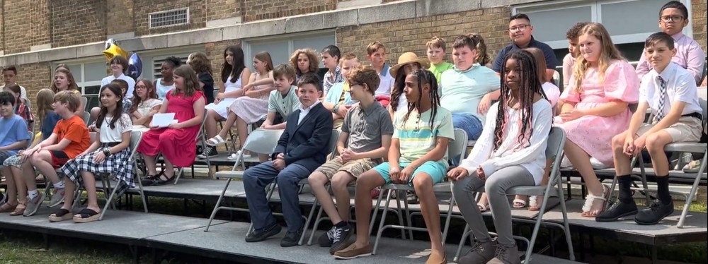 Some of the 5th grade Oaklyn Students sit patiently on stage at the start of their moving up ceremony